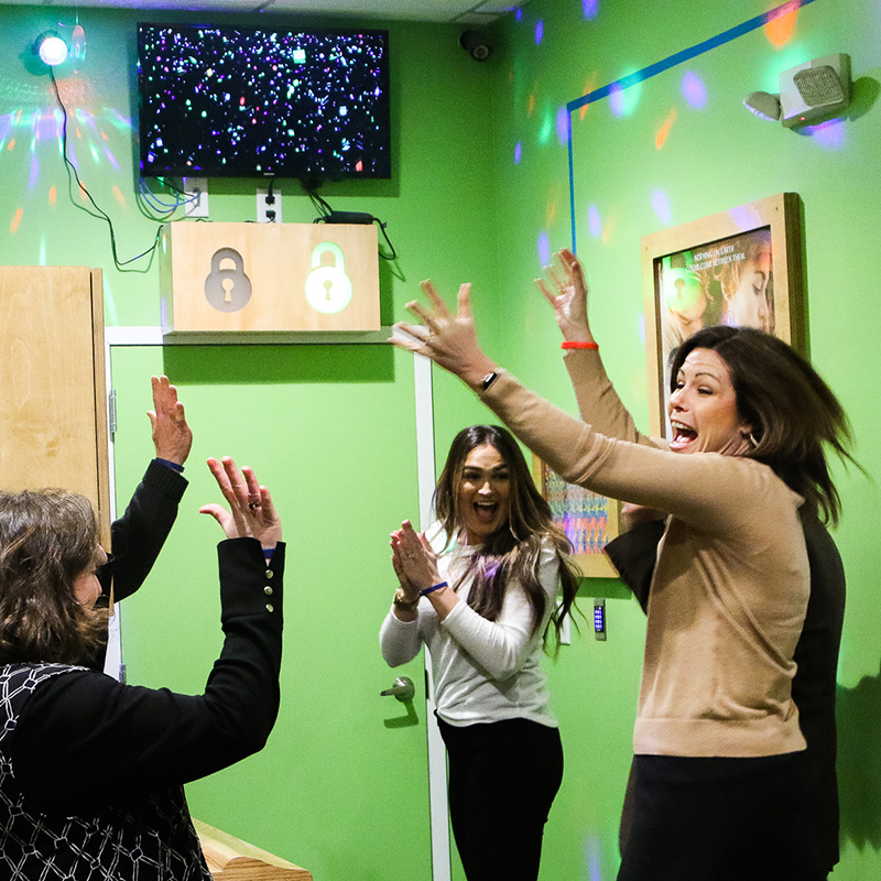 Players cheering with their hands in the air after escaping a room